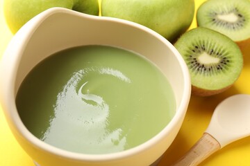 Baby food. Tasty puree in bowls and different ingredients on yellow background, closeup