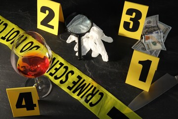 Forensic expert. Yellow crime scene tape, markers and evidences on black table, above view