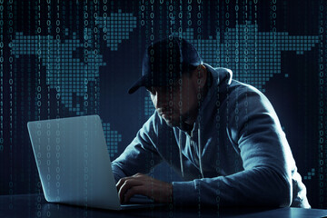 Cyber attack. Hacker working on laptop at table against world map. Binary code around him