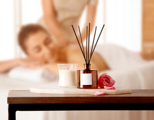 Spa therapy. Woman receiving massage on table and composition with aromatic reed air freshener in...