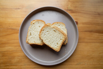 A close-up of three crisp, golden toasted bread slices on a clean white plate. The image captures...