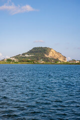 Fototapeta premium A tranquil view of Capo Miseno in Bacoli, Italy, seen from the calm blue waters under a bright summer sky