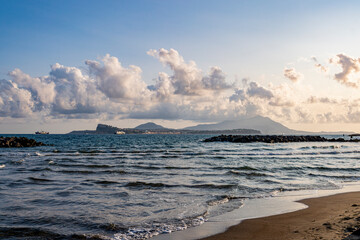 Golden sunset over the sea in Bacoli, Italy. In the distance, the islands of Ischia and Procida rise on the horizon beyond the calm waters