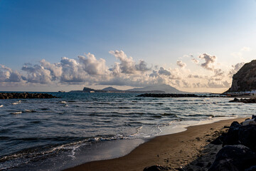 Golden sunset over the sea in Bacoli, Italy. In the distance, the islands of Ischia and Procida rise on the horizon beyond the calm waters
