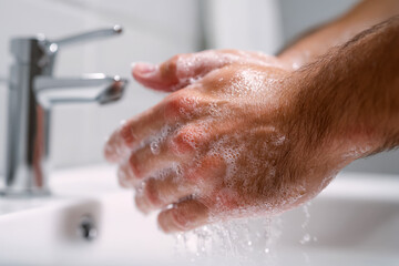 Person washing hands with soap under running water