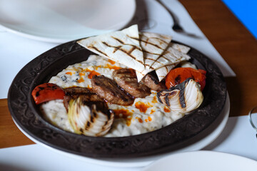 Delicious plate of grilled cutlets served with lavash fresh tomatoes and onions presented as hotel dinner on table