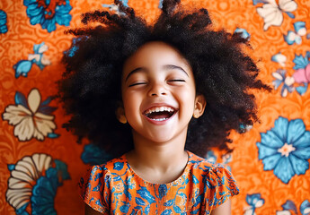 Joyful child with afro hair laughing against a vibrant floral background