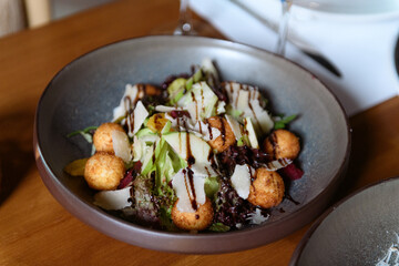 Fresh salad featuring cheese balls crisp apples leafy lettuce and delicious dressing served on a plate for hotel dining