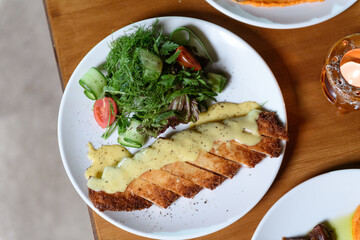 Tender meat served with creamy mashed potatoes and fresh salad on a plate for a satisfying hotel dining experience