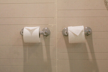 Toilet tissue paper in holder on tiled wall in bathroom. Modern restroom interior detail.
