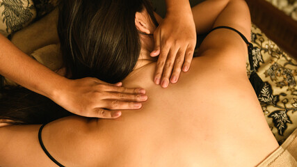 Professional massage therapist giving soothing back treatment to guest in elegant hotel spa environment