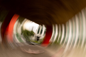 Coluna de concreto de cor vermelha retratada com efeito de giro produzido por um movimento da câmera fotográfica. 