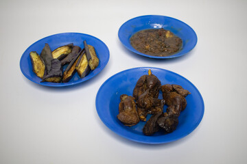 A simple traditional meal consisting of fried eggplant, chicken liver and spicy sauce on a blue plate.
