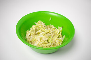 Shredded cabbage salad in a bright green plastic bowl on a white background.