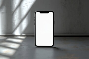 A modern smartphone with a blank white screen standing upright on a concrete surface with soft natural light and shadows from a window