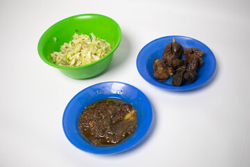 A simple meal consisting of chili sauce, stir-fried cabbage, and fried chicken liver served on a...