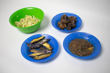 A simple meal with fried eggplant, chili sauce, stir-fried cabbage, and fried chicken gizzards.