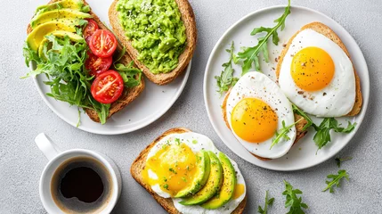 Selbstklebende Fototapeten Delicious flat lay of brunch spread with avocado toast, fried eggs, fresh arugula, cherry tomato, and cup of black coffee © jes2uphoto