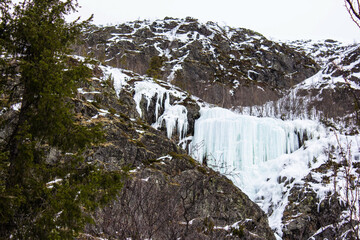  Stunning frozen waterfall on a rocky mountain covered with snow and ice. Wild winter landscape...
