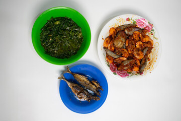 A delicious home-cooked meal with eggplant prawns, fried fish and stir-fried vegetables.
