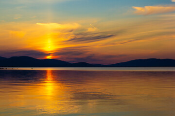 Golden sunset over tranquil lake with colorful sky and smooth reflections. Serene evening scene...
