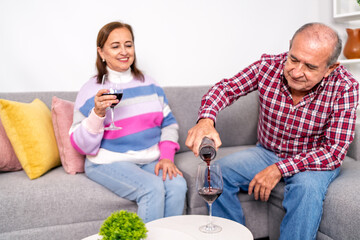 Senior couple enjoying wine together on sofa in living room
