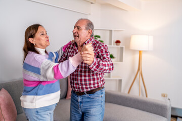 Happy senior couple dancing together in living room