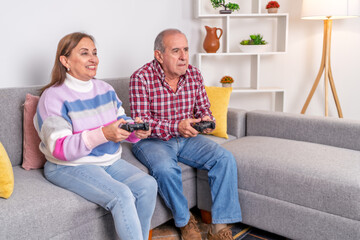 Happy senior couple playing videogames on the couch at home