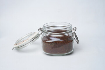 Glass jar filled with ground coffee isolated white background