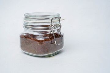 Glass jar filled with ground coffee isolated white background