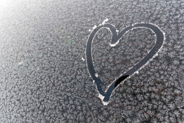 Heart Sign on car windshield covered in frost or ice crystals