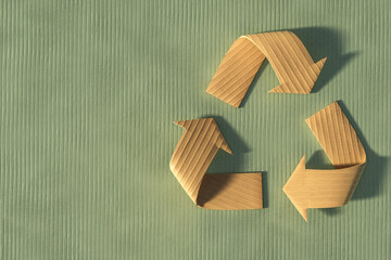 3D render of a recycle symbol made from corrugated cardboard on a green textured background, representing sustainable and eco-friendly packaging design.