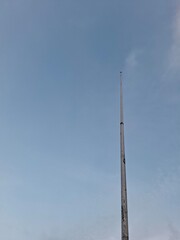 Obraz premium A tall, weathered tower reaching towards a clear blue sky. The image captures a sense of tranquility and openness, ideal for themes related to communication, height, or urban infrastructure.