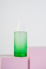 Green glass cosmetic bottle, Skin care or sunscreen cosmetic with stylish props on white background.