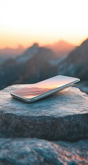 Smartphone rests on a rock, mountain sunset backdrop