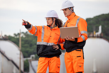 Engineers Collaborating at Industrial Site with Storage Tanks, Team of Engineers Conducting...