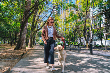 A woman is walking her dog along a tree-lined path in Mexico City’s Polanco neighborhood,...