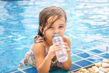 Tired child drinks water in the pool