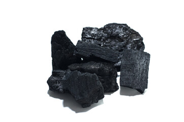 Heap of dark black carbon charcoal pieces on a bright white background, showcasing textures and...