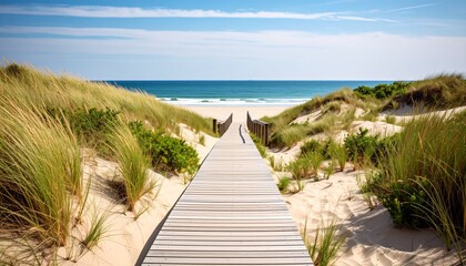 Wooden boardwalk leads to a sandy beach with ocean view under a clear blue sky.