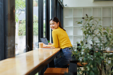 Portrait of Creative young asian woman thinking and working on tablet laptop at coffee...