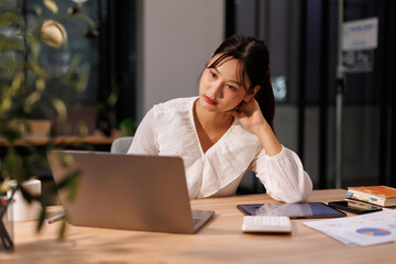 Fototapeta premium Portrait of business Young Asian woman is sitting at a desk with a laptop open in front of her. She is thinking and planning his project, remote working at workplace. 