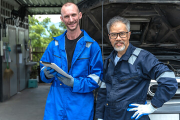 Caucasian male mechanic fixing car with male senior technician in repair shop