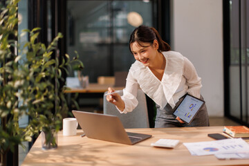 Portrait of business Asian woman Accounting using tablet calculating income-expenditure and...