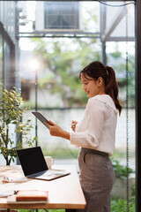 Portrait of business Asian woman Accounting using tablet calculating income-expenditure and...