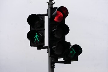 Urban crosswalk light with red and green signals in cloudy weather