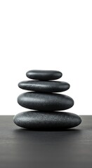 Stacked black spa stones on dark surface with white background