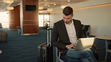 Focused businessman working on laptop in modern airport terminal waiting area - Powered by Adobe