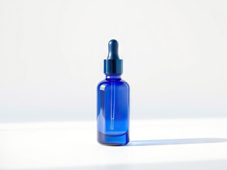 Blue glass dropper bottle with sleek design, placed on white surface under soft natural light