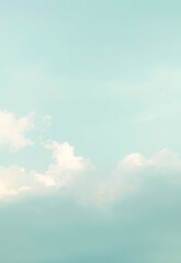 Soft pastel blue sky with fluffy white clouds creating serene and tranquil atmosphere